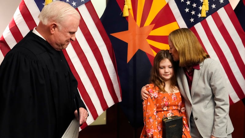 FILE - The new Arizona Attorney General Kris Mayes, right, a Democrat, kisses daughter Hattie,...