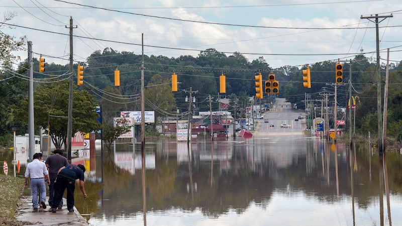 A passerby checks the water depth of a flooded road, Saturday, Sept. 28, 2024, in Morganton,...