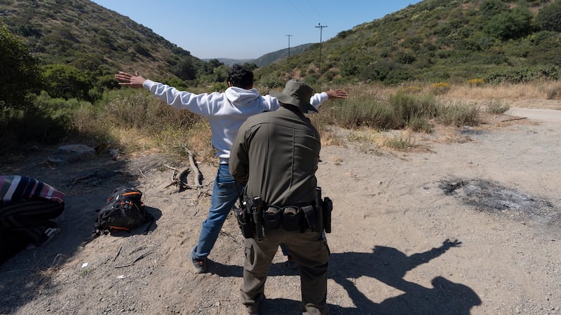 FILE - A Border Patrol agent checks a migrant seeking asylum before the man is transported and...