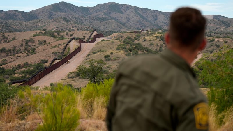 Border patrol agent Pete Bidegain looks from a hilltop on the U.S. side of the US-Mexico...