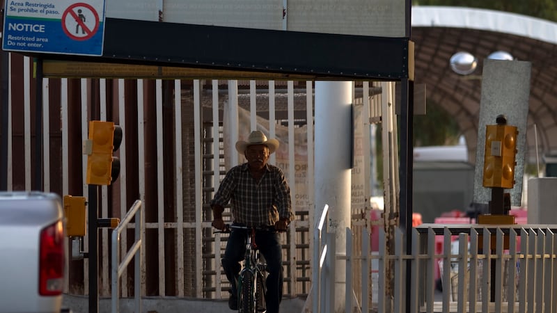 FILE - A man rides his bike through the Mexican port of entry in San Luis Rio Colorado,...