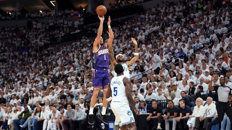 Phoenix Suns guard Devin Booker (1) shoots over Minnesota Timberwolves guards Nickeil...