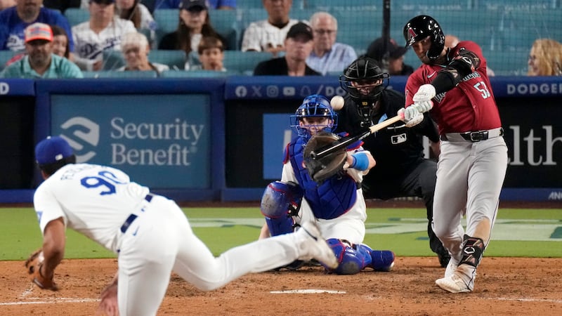 Arizona Diamondbacks' Christian Walker, right, hits a three-run home run as Los Angeles...