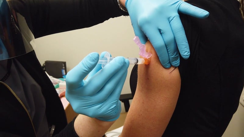 A medical professional is giving a person a vaccination.
