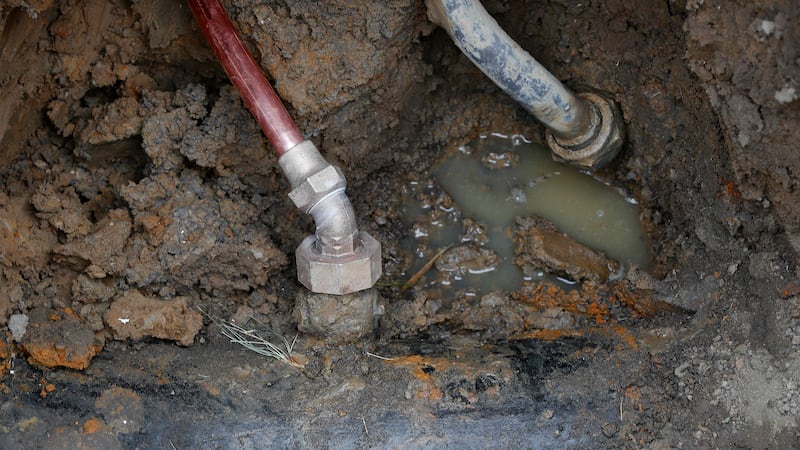 FILE - A copper water supply line, left, is shown connected to a water main after being...